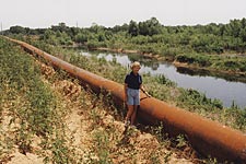 Jackie Carver stands beside peline pumping sediment to South Dallas - 1997